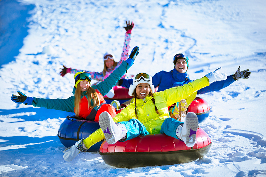 Group of young people snow tubing. 