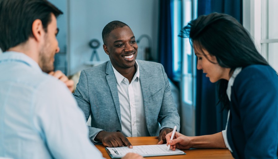 Two people talking to a real estate agent.